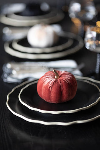 The Small Dusky Rose Velvet Pumpkin styled on some dark plates as part of a Halloween tablescape.