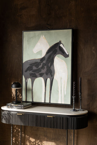 The Stallion Shadow Canvas Art Print styled above a console table in front of a dark wall, with candlestick holders, books and a black table lamp.