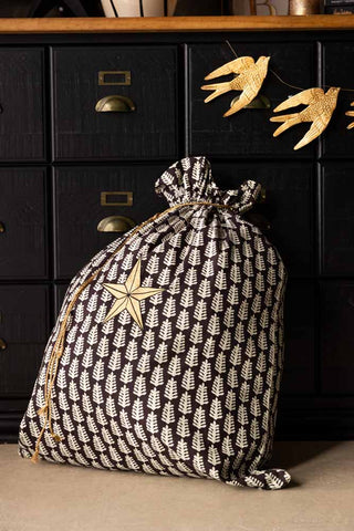 The Star Printed Christmas Sack styled in front of a black and wooden unit with a bird garland.