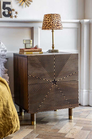 The Starburst Bedside Table styled next to a bed with a lamp and home accessories on the top.