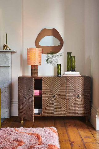 The Starburst Sideboard styled with various home accessories in a living room, with one of the doors slightly open.