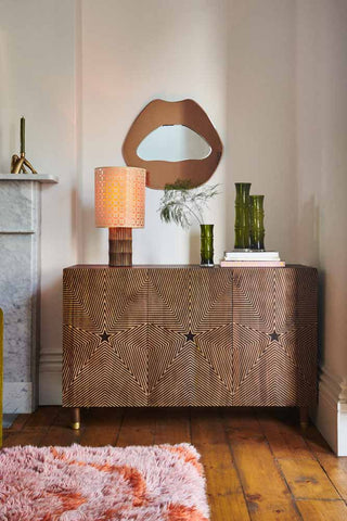 The Starburst Sideboard styled in a living room with vases, a lamp, a mirror, a candlestick holder and a rug.