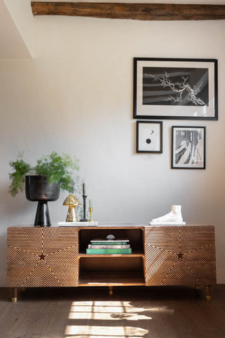 The Starburst TV Unit styled in a living room with various home accessories, a plant and some art prints on the wall.