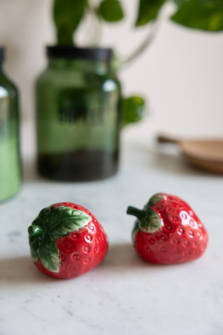 The Strawberry Salt & Pepper Shakers styled on a marble surface with other kitchen accessories.