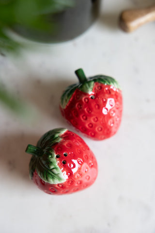 The Strawberry Salt & Pepper Shakers seen from above on a marble surface.