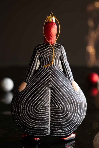 The reverse side of the Stripe Bowie Inspired Christmas Tree Decoration, styled on a dark surface with baubles and fairy lights in the background.