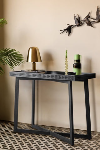 The Stylish Mango Wood Console Table with some accessories on, styled next to a plant with a bird ornament on the wall.