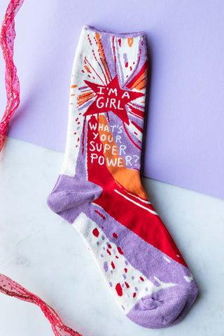 One of the Superpower Womens Socks displayed on a lilac and white background with some red ribbon.