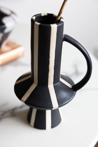 Close-up of the Tall Striped Black & White Vase With Handle styled on a marble table.