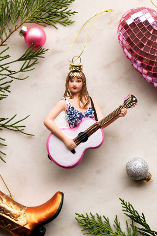 Image of the Taylor Inspired Christmas Tree Decoration on a white surface next to a cowboy boot and pink disco heart decoration.