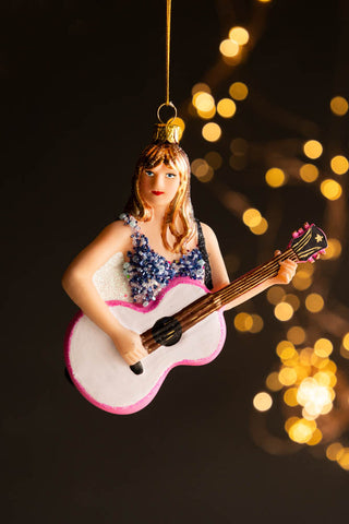 The Taylor Inspired Christmas Tree Decoration hanging in front of a dark background with fairy lights.