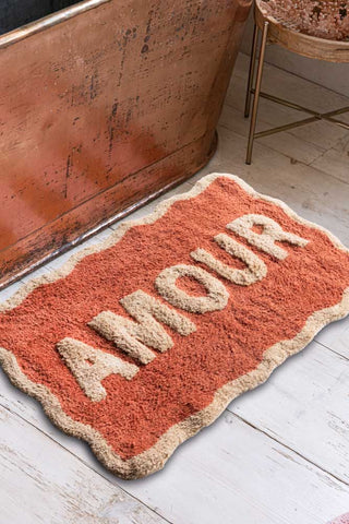 The Terracotta Amour Bath Mat displayed on a bathroom floor next to a bath and side table.