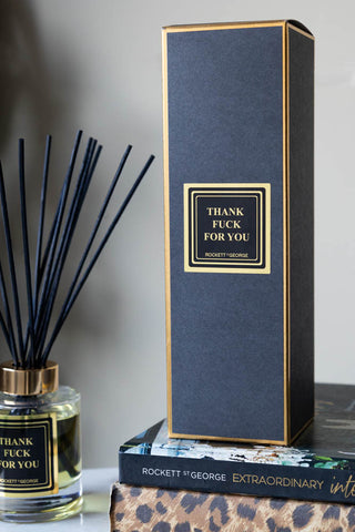 The box of the Thank Fuck For You Reed Diffuser - 150ml styled with the diffuser and some books.