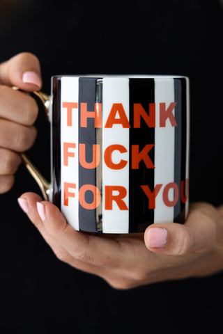 The Thank Fuck For You Stripe Mug being held in a model's hands.