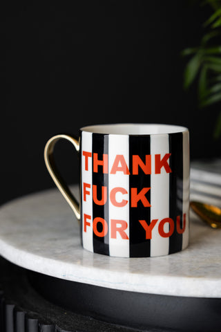 The Thank Fuck For You Stripe Mug styled on a white marble surface.