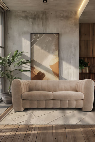 The Bowie Large Sofa In Luxe Kneedlecord Velvet Natural Whisper styled in a living room with a large plant and artwork.