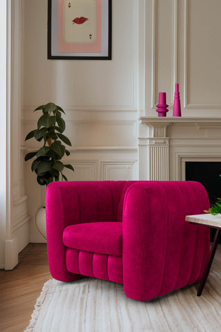 The Bowie Love Seat In Luxe Needlecord Velvet Harry's Pink styled in front of a fireplace next to a table, with a plant, art print and two pink vases.