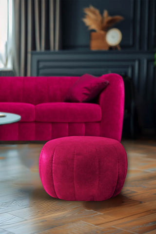 The Bowie Stool In Luxe Needlecord Velvet Harry's Pink on a wooden floor in a living room, with the matching sofa styled in the background.