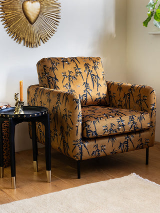 The The Edie Bamboo & Golden Glow Velvet Armchair styled with a side table, rug, plant and various accessories.