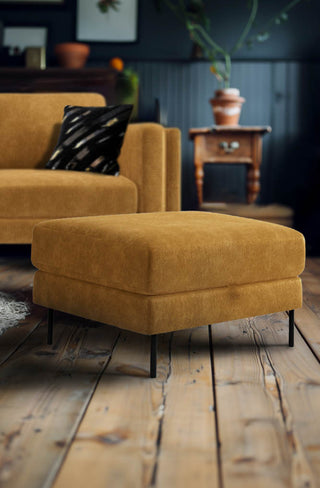 The Grace Foot Stool In Luxe Needlecord Velvet Golden Glow styled in a living room in front of the matching sofa.