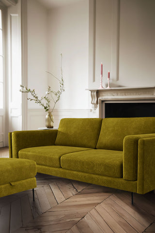 The Grace Medium Sofa In Luxe Kneedlecord Velvet Vintage Green styled in a white panelled room with a fireplace