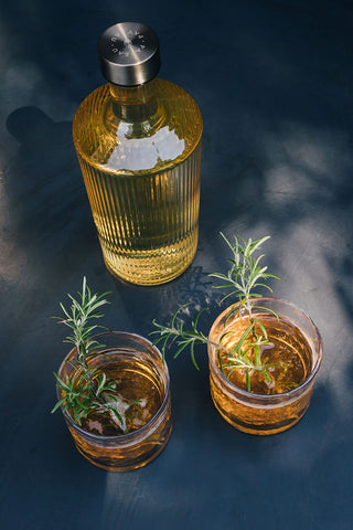 The Paveau - Gorgeous Ribbed Glass Carafe in Amber on a blue table with two drinks.