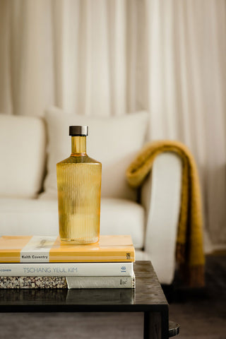 The Paveau - Gorgeous Ribbed Glass Carafe in Amber styled on a stack of books on a coffee table.