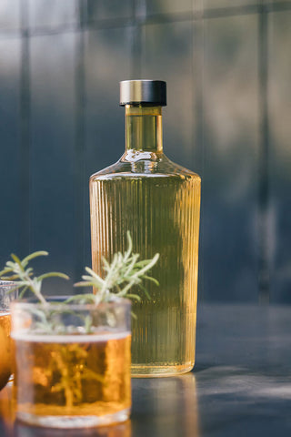 Close-up of The Paveau - Gorgeous Ribbed Glass Carafe in Amber styled with two drinks.