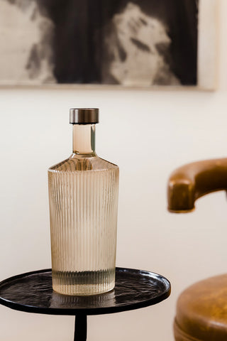 The Paveau - Gorgeous Ribbed Glass Carafe in Amber styled on a side table next to a chair.