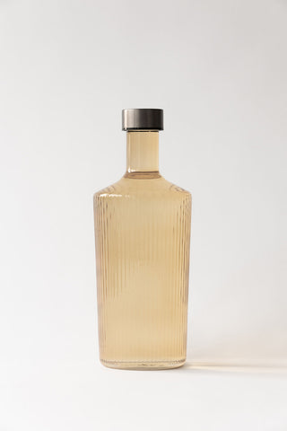 The Paveau - Gorgeous Ribbed Glass Carafe in Amber in front of a neutral background.