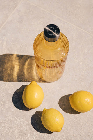 The Paveau - Gorgeous Ribbed Glass Carafe in Amber styled with lemons, seen from above.