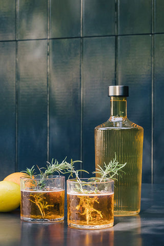 The Paveau - Gorgeous Ribbed Glass Carafe in Amber styled with two drinks and some lemons, in front of a tiled wall.