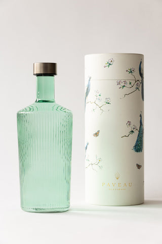 The Paveau - Gorgeous Ribbed Glass Carafe in Green with the box in front of a neutral background.