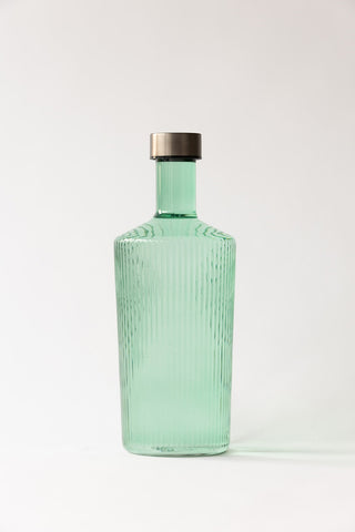 The Paveau - Gorgeous Ribbed Glass Carafe in Green in front of a neutral background.