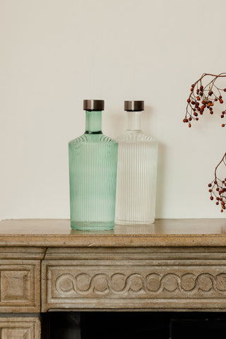 The Paveau - Gorgeous Ribbed Glass Carafe in Green styled with the white version on a fireplace ledge.