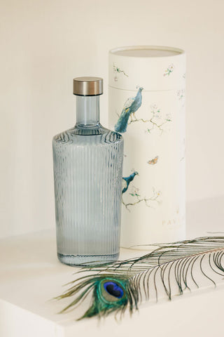 The Paveau - Gorgeous Ribbed Glass Carafe in Grey Blue styled with its box and a peacock feather.