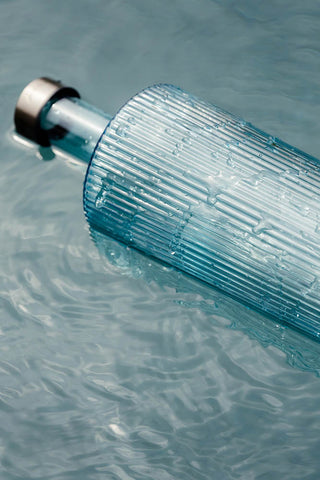 The Paveau - Gorgeous Ribbed Glass Carafe in Grey Blue floating in water.