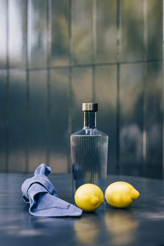 The Paveau - Gorgeous Ribbed Glass Carafe in Grey Blue styled with a napkin and two lemons.