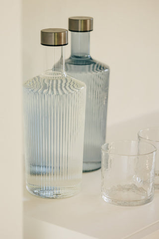 The Paveau - Gorgeous Ribbed Glass Carafe in White styled with the blue version and some glasses.