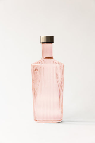 The Paveau - Gorgeous Ribbed Glass Carafe in Pale Pink in front of a neutral background.