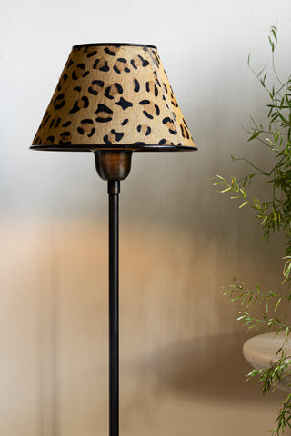 The Thin Table Lamp With Leopard Shade styled in front of a neutral wall next to a plant.