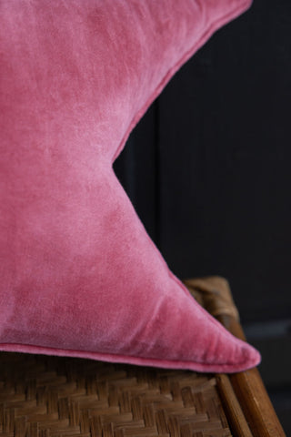 Close-up of the Velvet Star Cushion In Hot Pink displayed on a wicker bench.