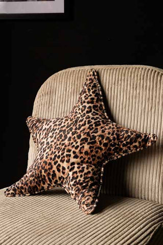 The Velvet Star Cushion In Leopard Print displayed on a chair.