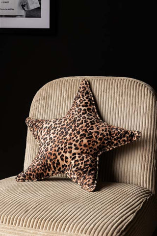 The Velvet Star Cushion In Leopard Print styled on a neutral coloured chair.