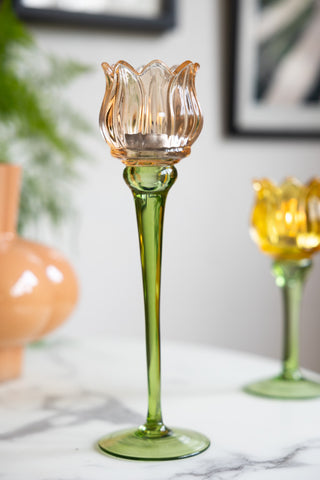 The Vintage-Style Orange Glass Flower Candle Holder styled on a white table.