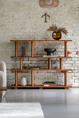 The Large Freestanding Tiered Display Shelves styled in front of a brick wall with various home accessories on.