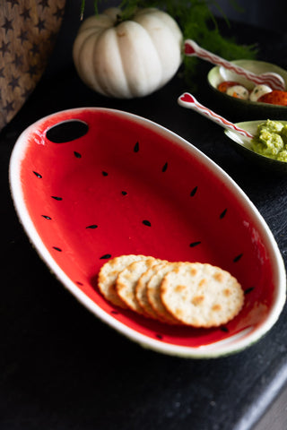 A Lifestyle image of the Watermelon Serving Plate served on a dark table top, styled with autumnal props