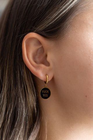 One of the Waterproof Fuck Yes Gold Charm Earrings styled in a model's ear.