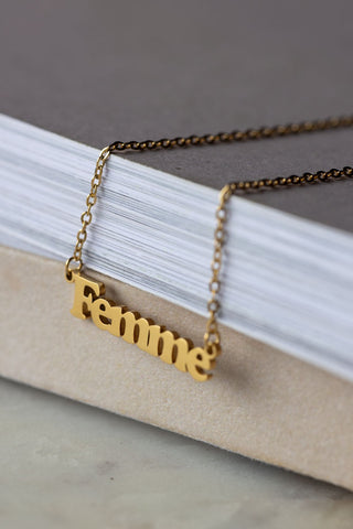 The Waterproof Gold Femme Necklace displayed on the corner of a neutral surface.