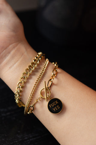 The Waterproof Gold Fuck Yes Charm Bracelet styled with two other bracelets on a model's wrist.